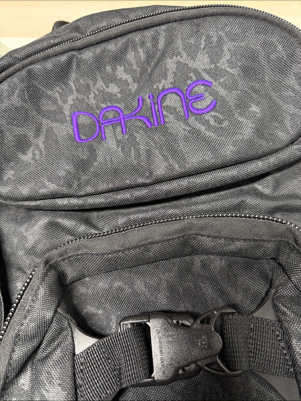 Dakine Heli Pro backpack features a black camouflage pattern and purple brandin - Picture 2 of 6